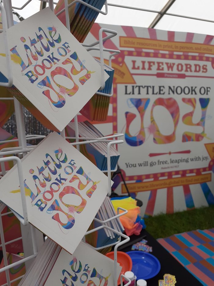 Copies of Little Book of Joy on a stand with 'Little Nook of Joy' banner in the background